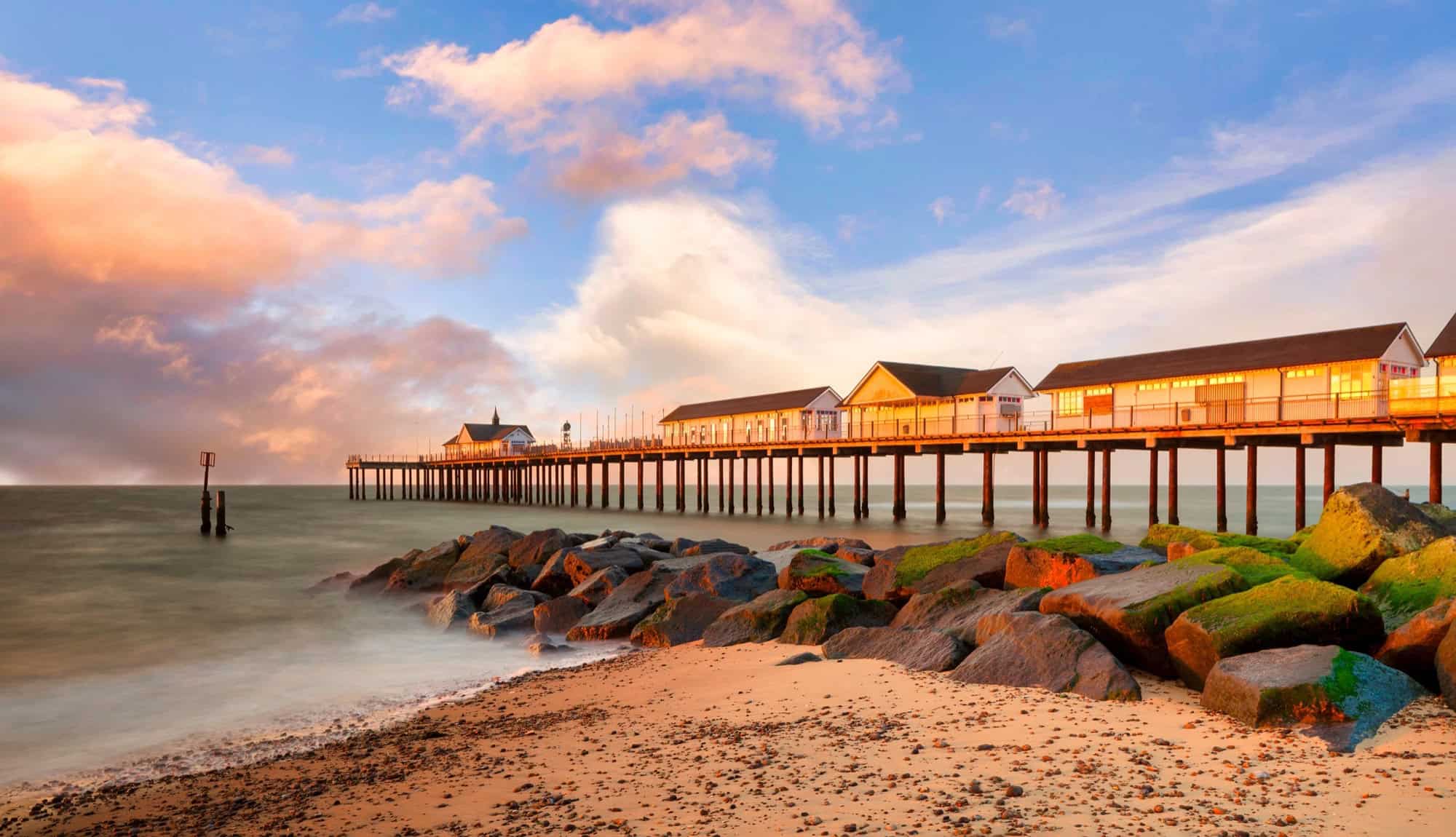 Sunrise illuminating the Southwold Pier and gentle waves on the Suffolk coast.