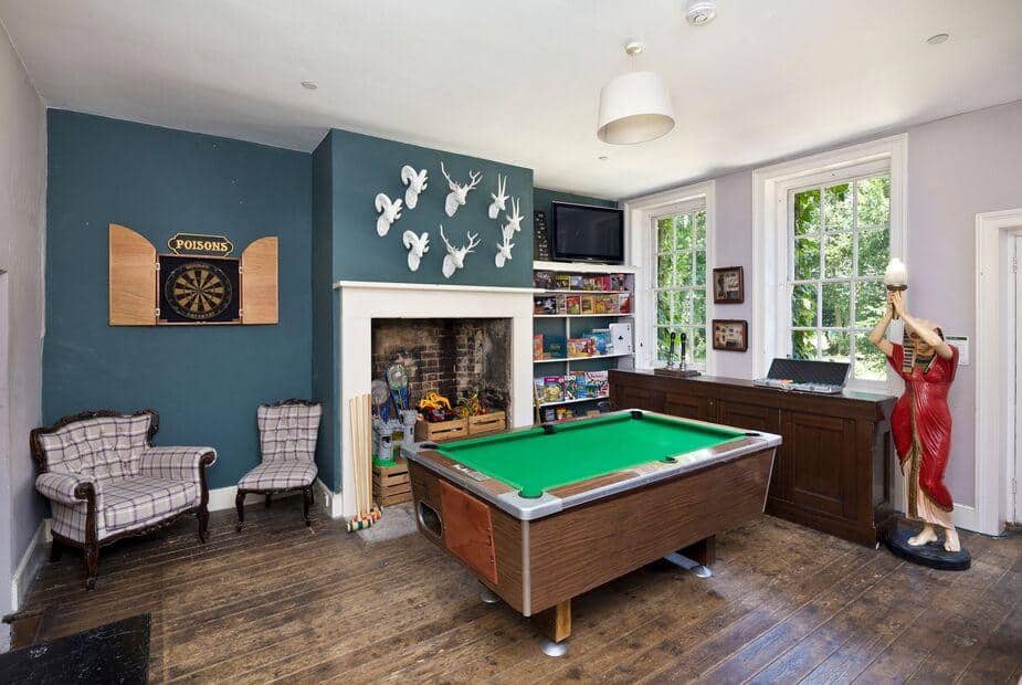 Cottage games room with pool table, dartboard and armchairs