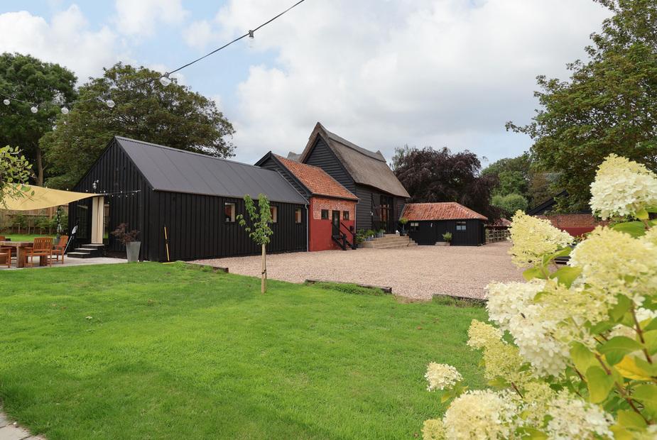 Halcyon Barn with outdoor seating area and gravel driveway in garden setting