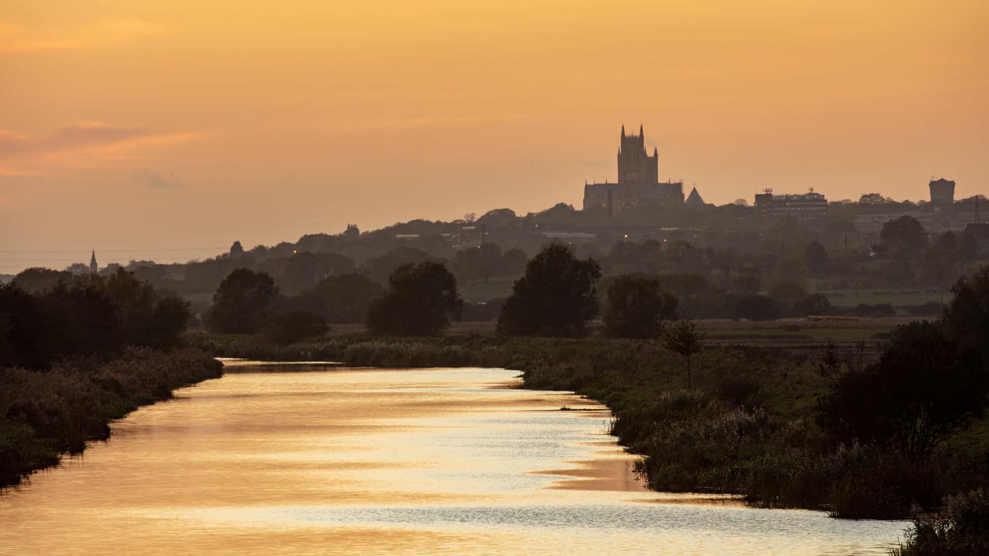 Golden sunset silhouette of Lincoln Cathedral sitting high on the hill overlooking the River Witham.