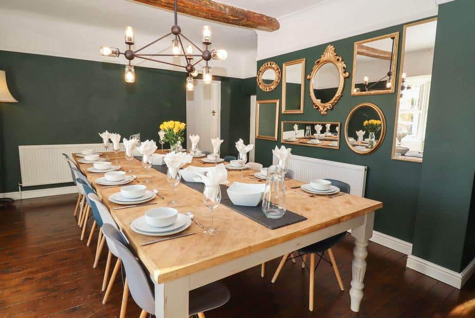 Cottage dining room with long table, set for twelve, and wall decorated with mirrors