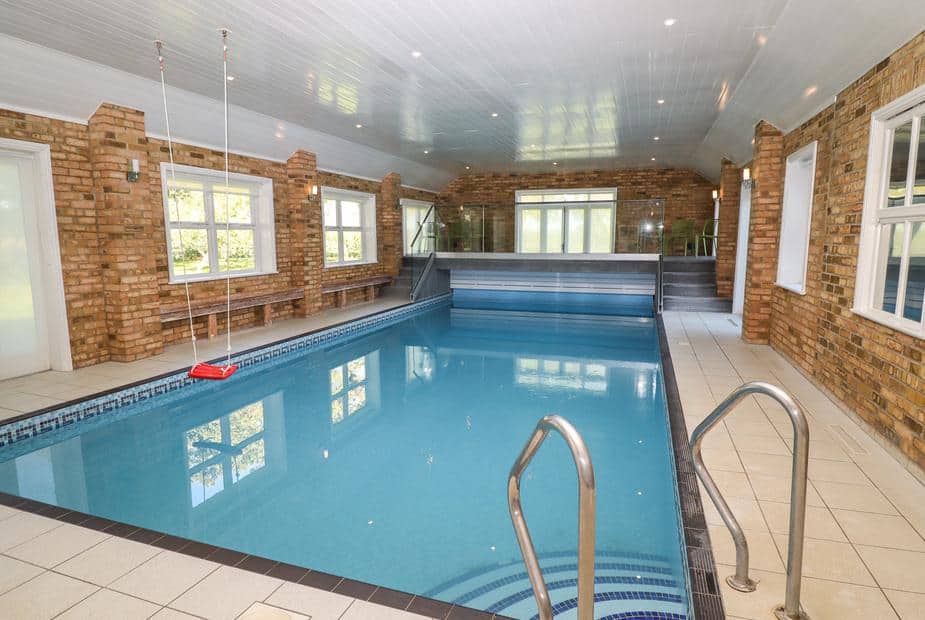 Indoor cottage pool with brick walls and metal handrails