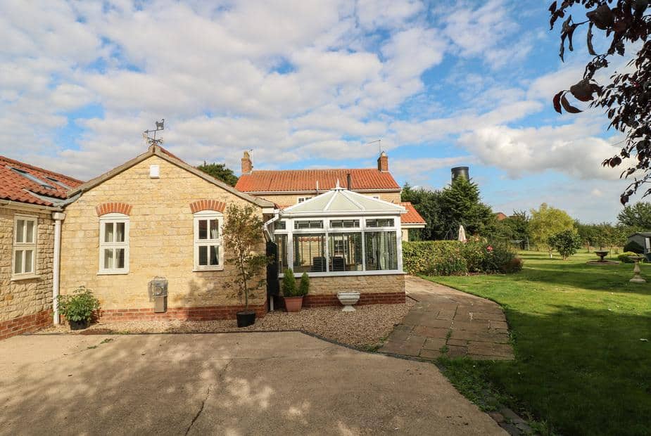 Millcott with conservatory overlooking a large garden lawn and patio area