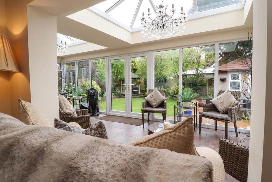 Cottage conservatory with wicker chairs and garden view through glass doors