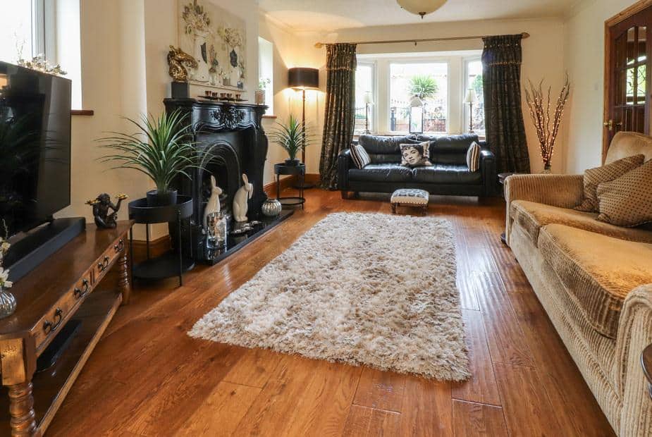 Cottage living room with fireplace, two sofas and a large rug on wooden floor