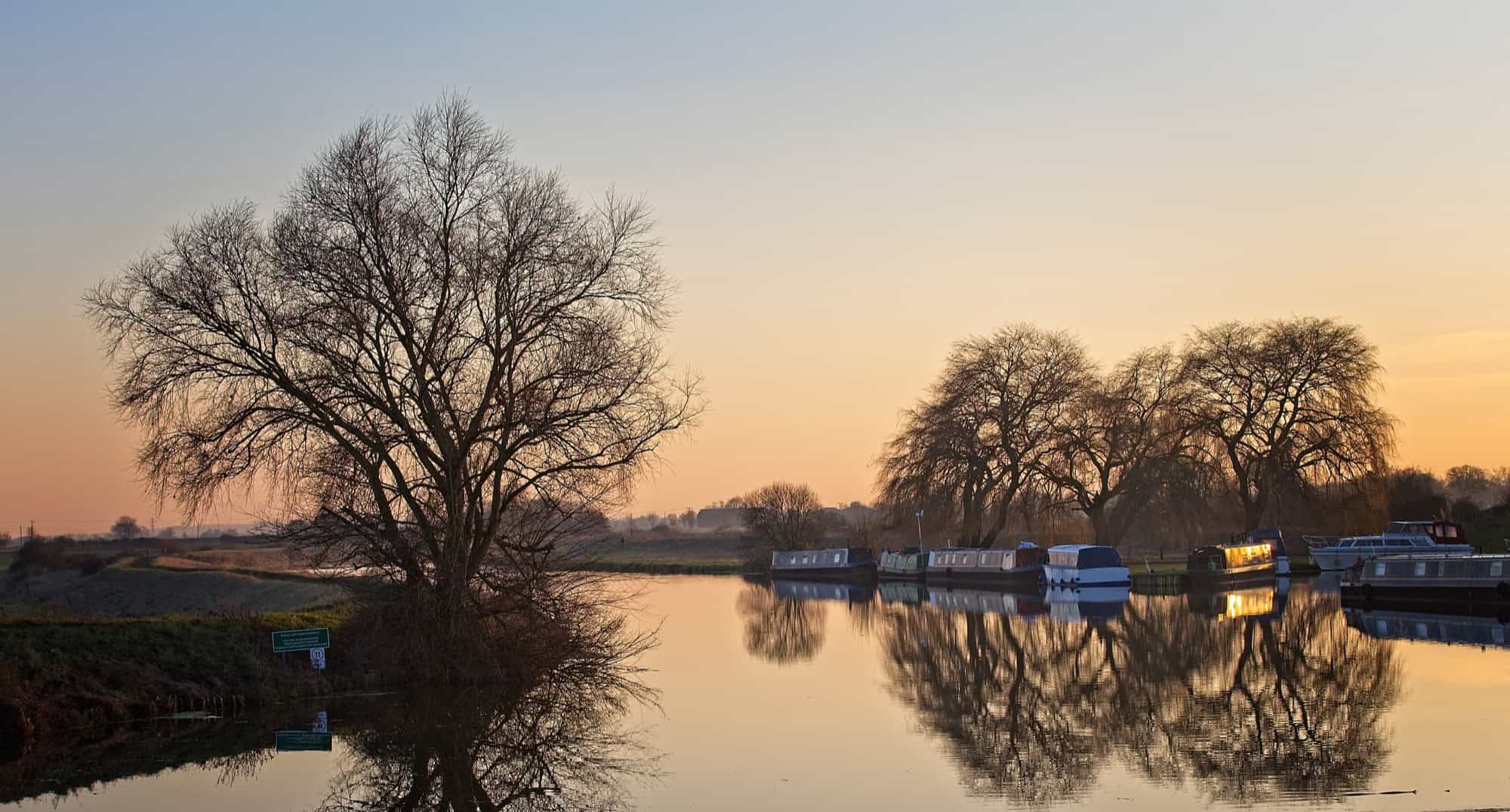 Sunset reflecting on the calm waters of the River Cam in the Cambridgeshire Fens.