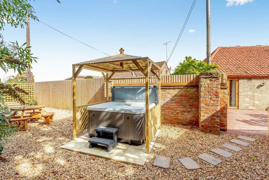 Cottage garden with covered hot tub and picnic bench on gravel patio