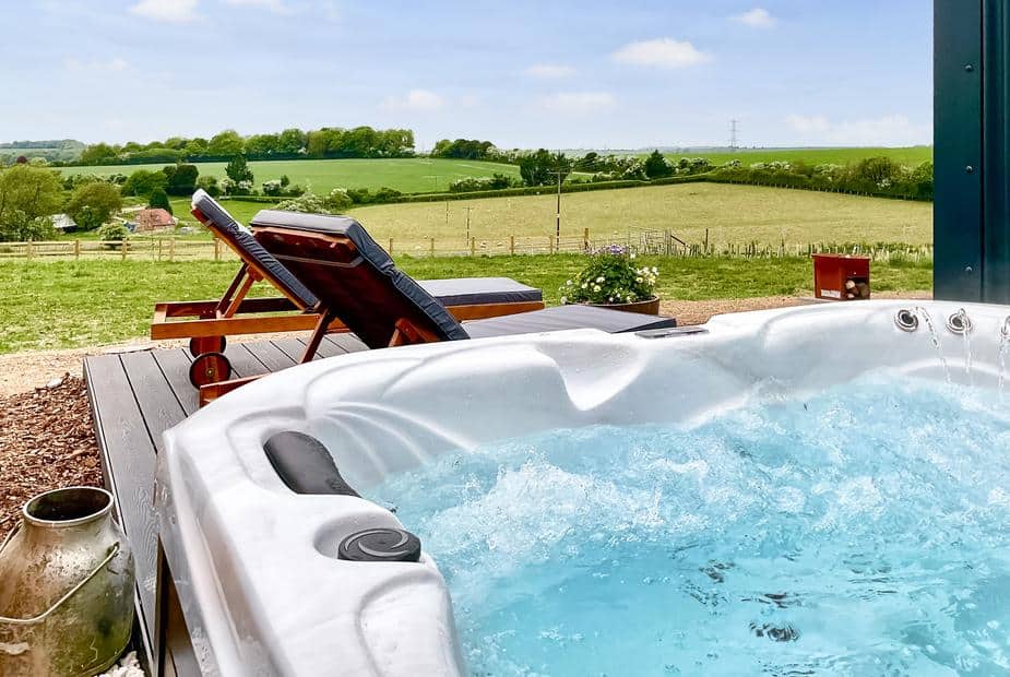 Lodge deck with hot tub and sun loungers overlooking fields