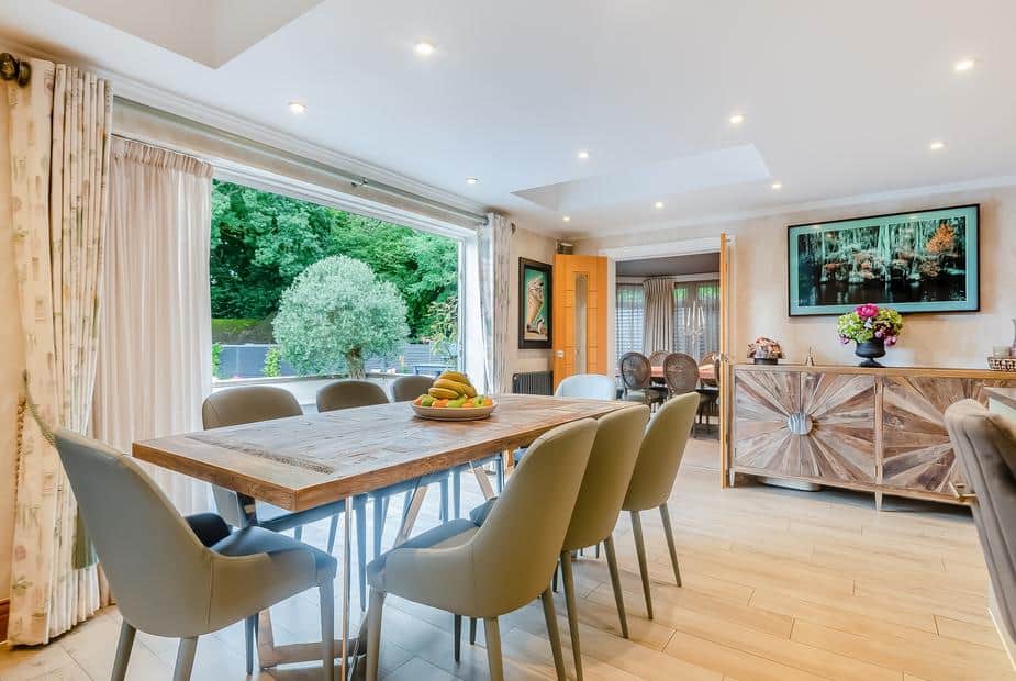 Cottage dining room with wooden table, chairs, and doors open to garden patio