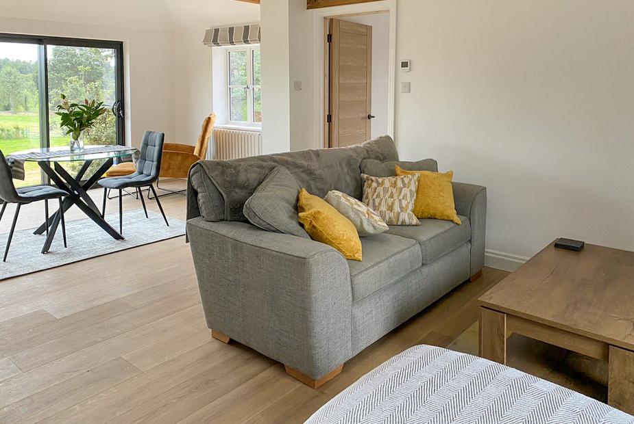 Cottage lounge with grey sofa and dining table by sliding glass doors