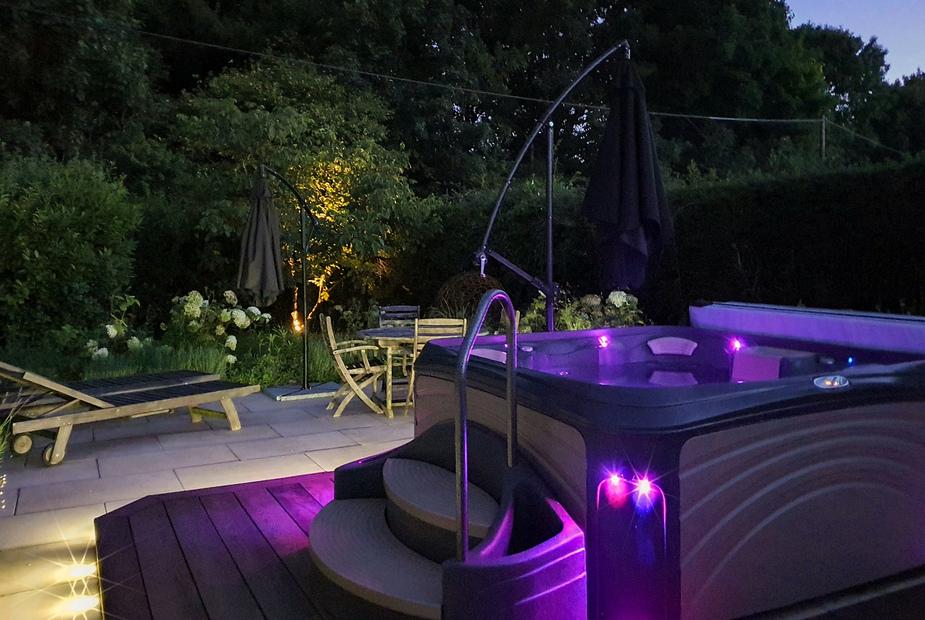 Cottage patio with hot tub and seating area at dusk