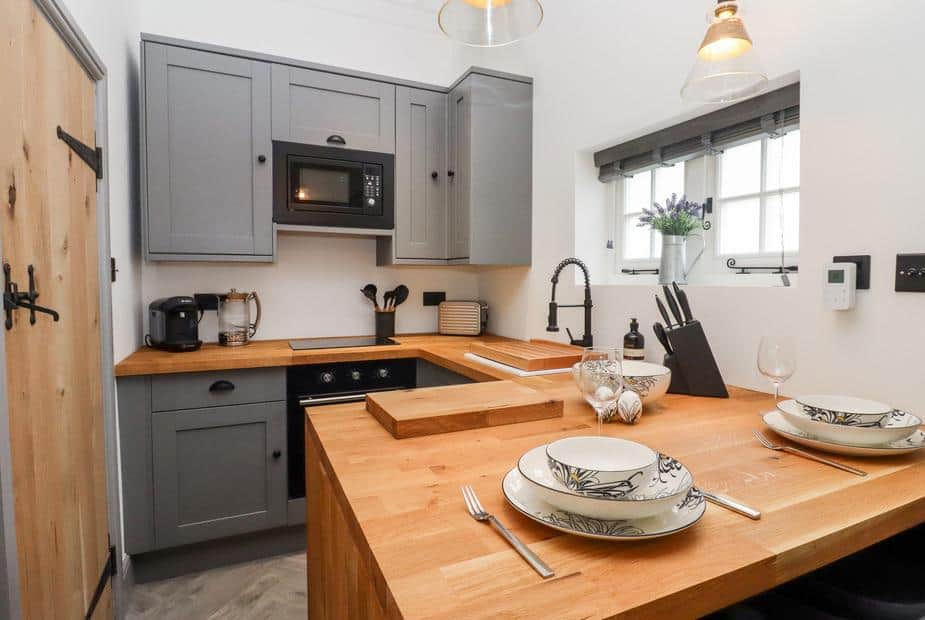 Kitchen with wooden countertop, grey cabinets and dining set for two