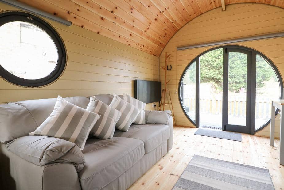 Lodge lounge with grey sofa and circular glass doors to outside deck