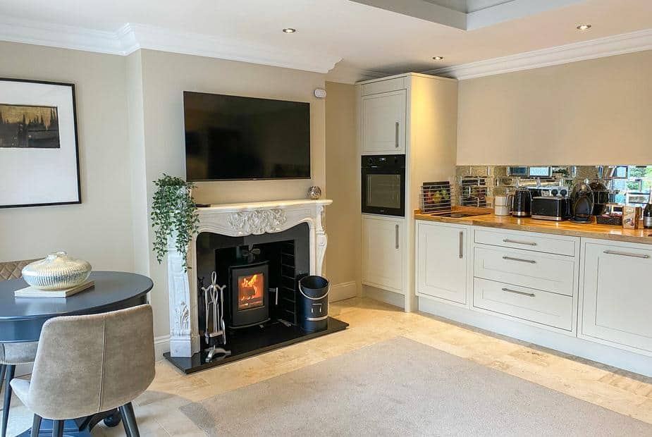 Cottage kitchen with wood burner, TV above mantel and dining table with two chairs