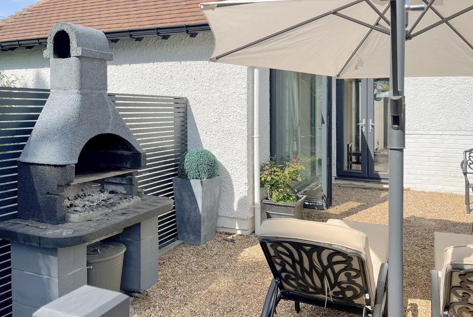 Cottage patio with outdoor fireplace, sun loungers and parasol