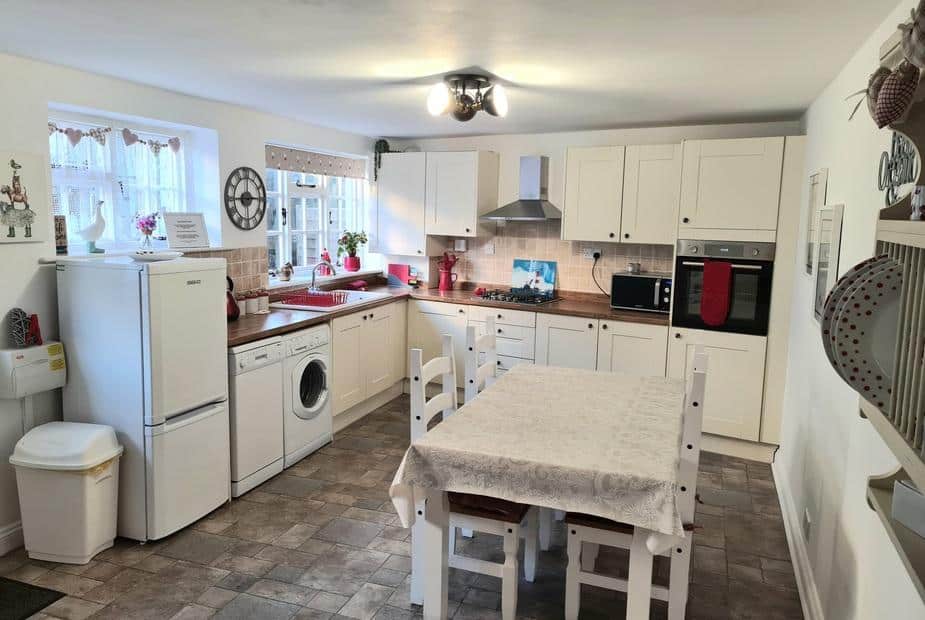 Cottage kitchen with dining table, washing machine, and fitted oven.