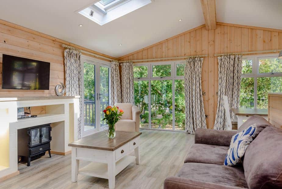 Lodge living room with sofa, TV, and large windows overlooking trees