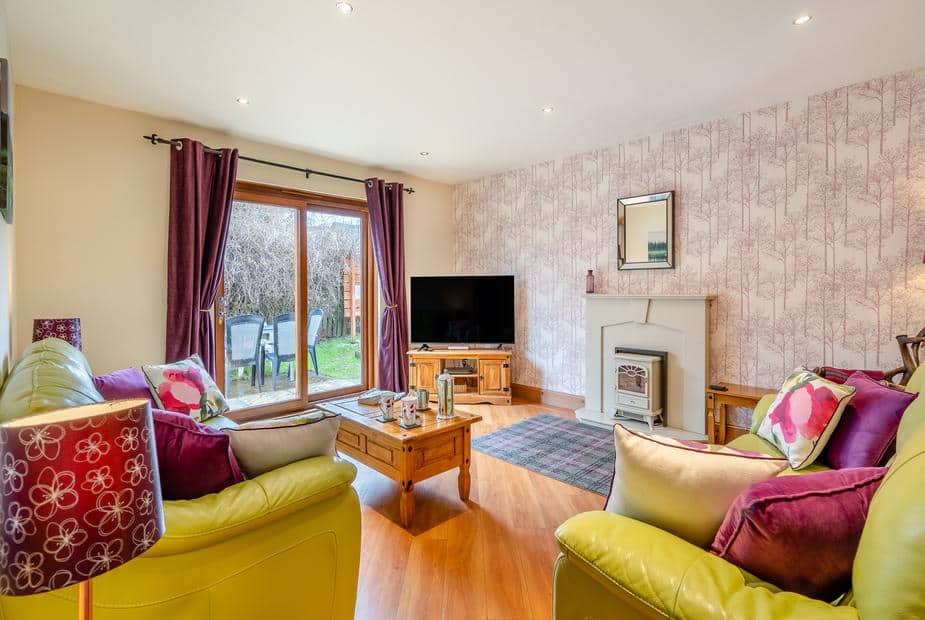 Cottage lounge with sofas, television, fireplace and sliding doors to garden patio