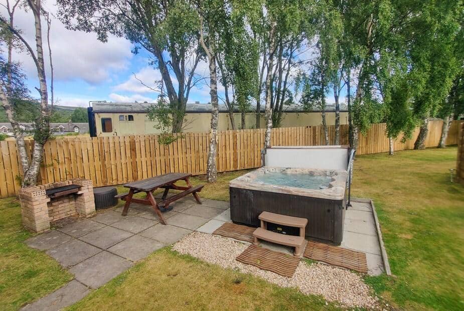 Lodge garden with hot tub, picnic bench and brick barbecue
