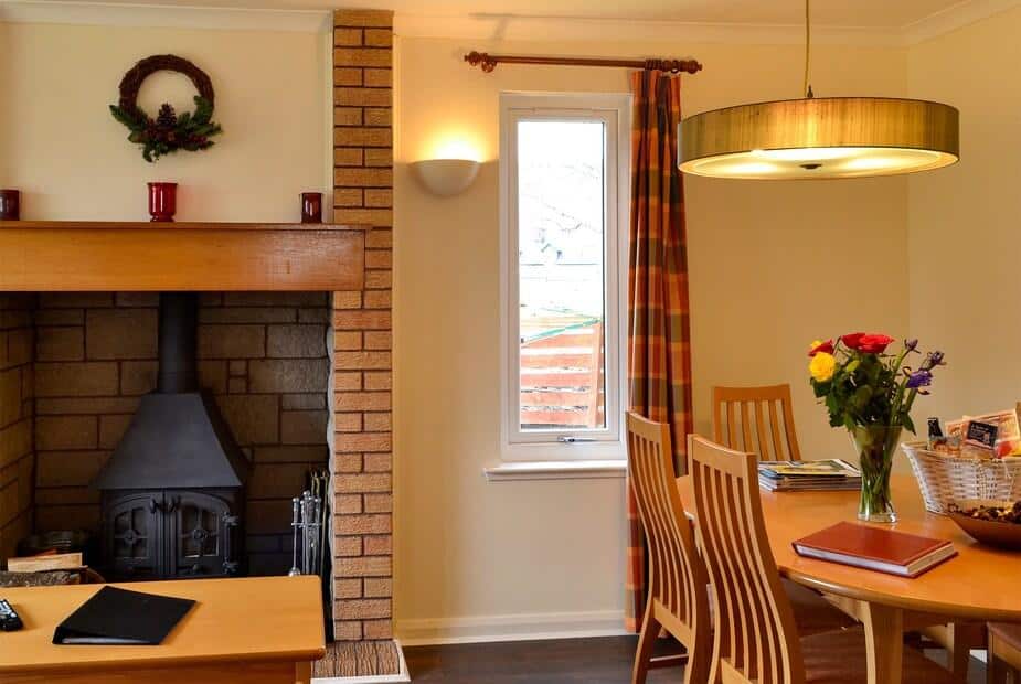 Dining area with wooden table, chairs, and log burner in brick fireplace