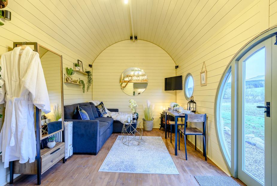 Lodge living area with grey sofa, dining table and round mirror on wall