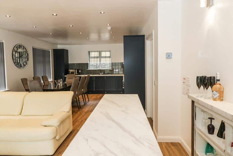 Open-plan cottage kitchen and dining area with a drinks shelf and cream sofa.