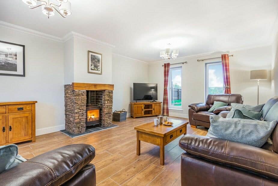 Living room with stone fireplace, leather sofas and wooden coffee table