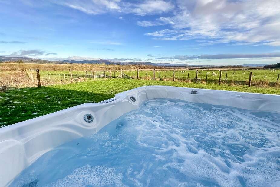 Hot tub in garden with countryside views and fenced lawn