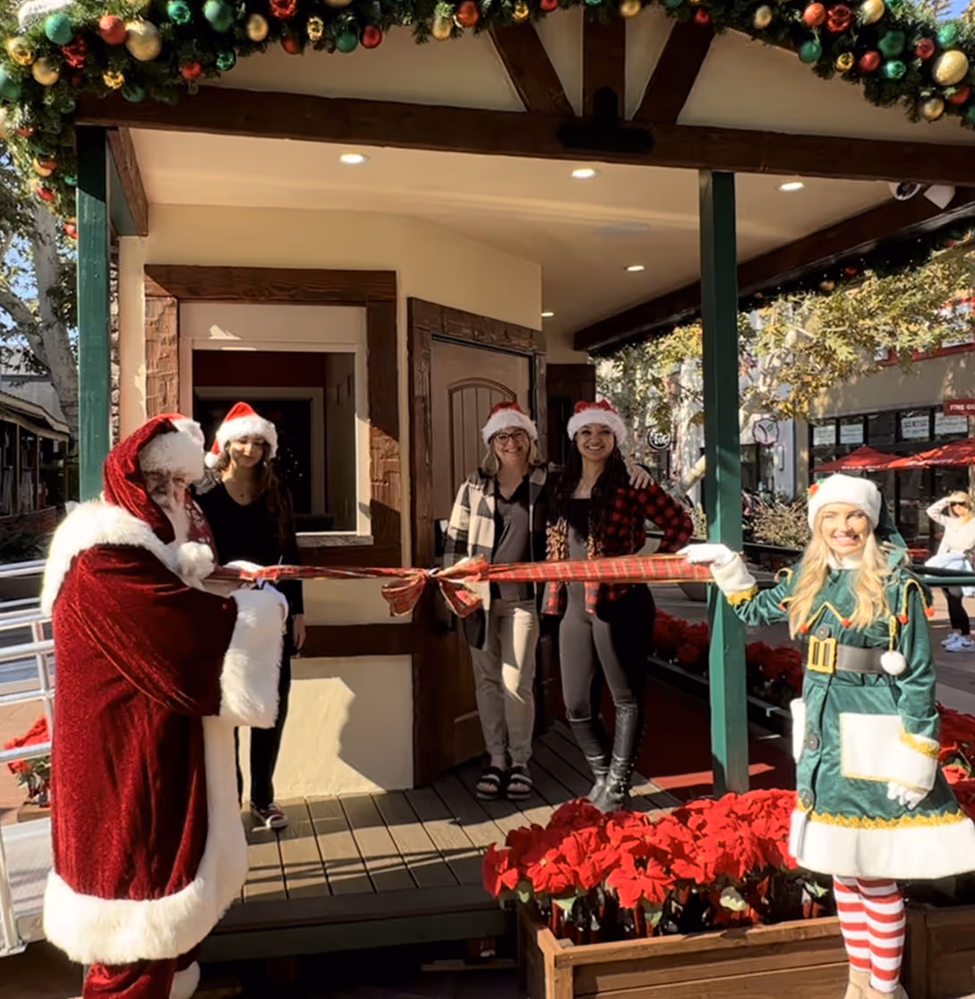 Santa and Holiday Magic Studios team cutting ribbon at grand opening with elf mascot