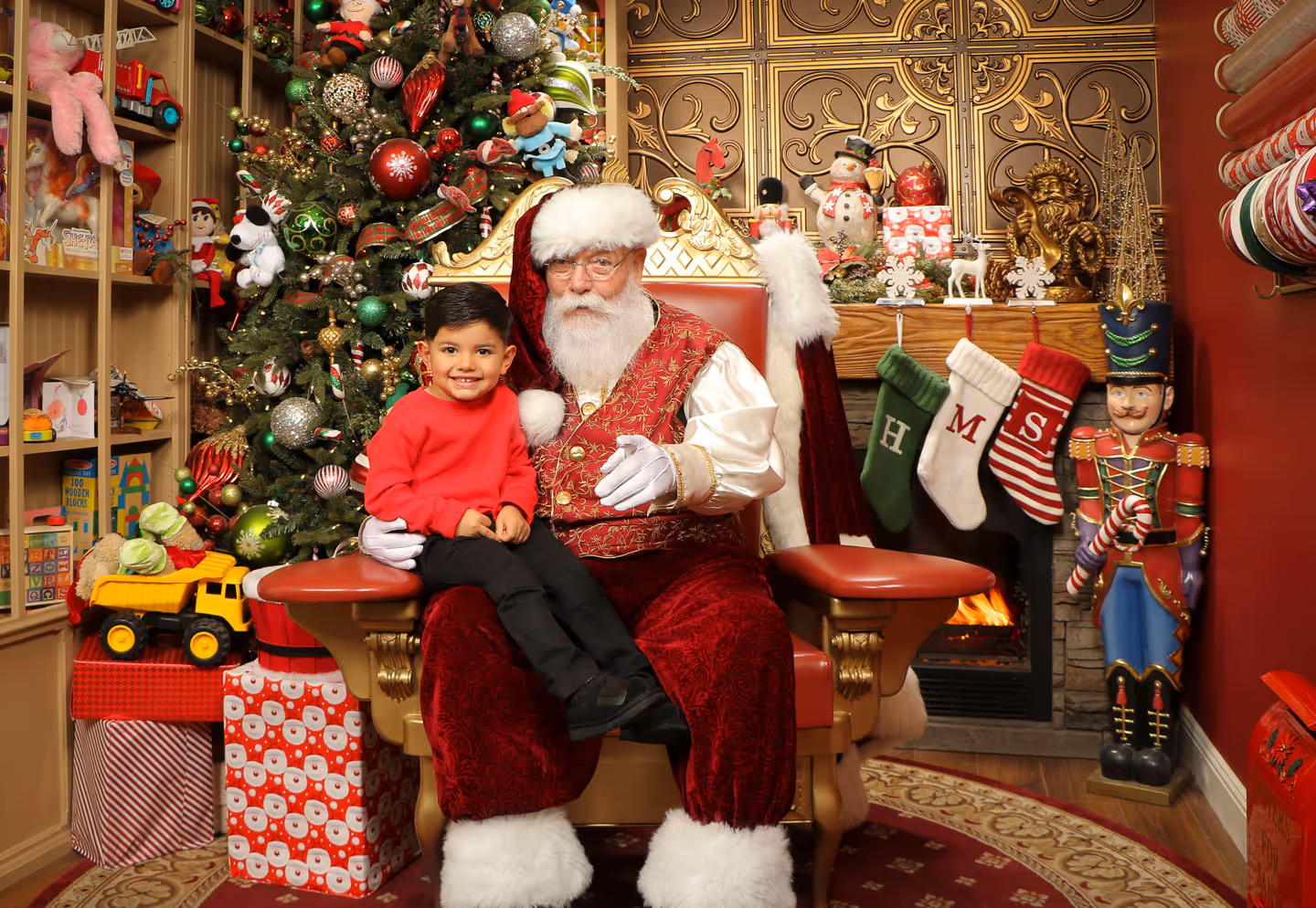 Young boy posing with Santa in a festively-decorated photo studio