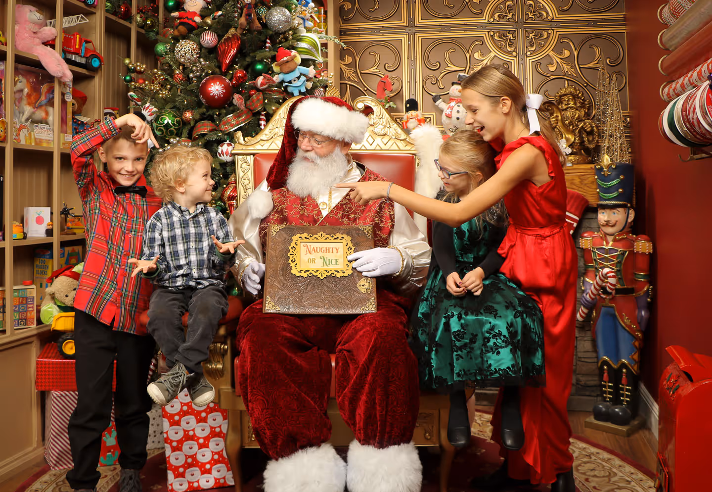 Four siblings in a silly pose with Santa in a festive Christmas studio