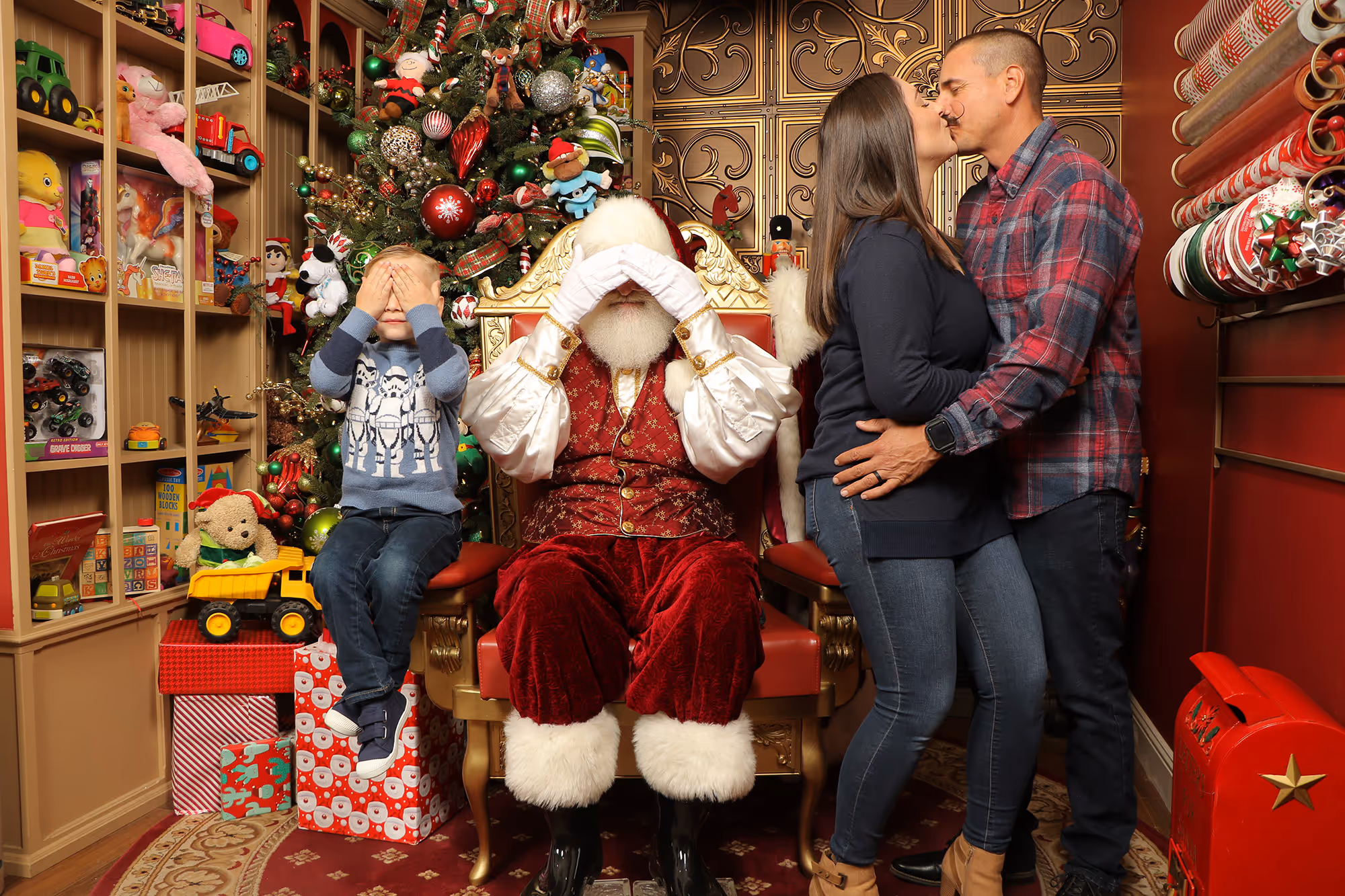 Funny Santa photo with mom and dad kissing while Santa and the son cover their eyes