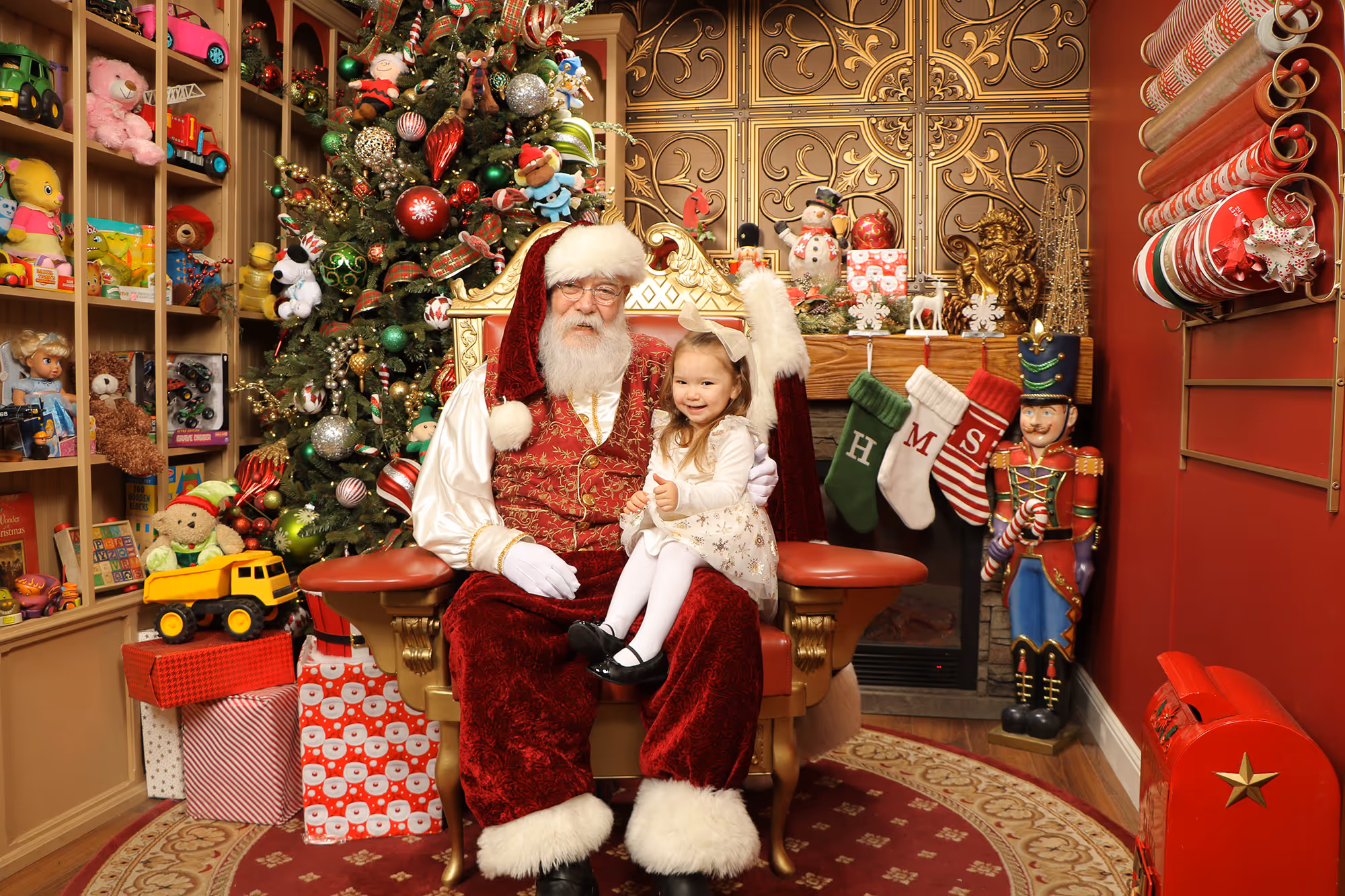 Young girl smiling on Santa's lap in front of Christmas tree