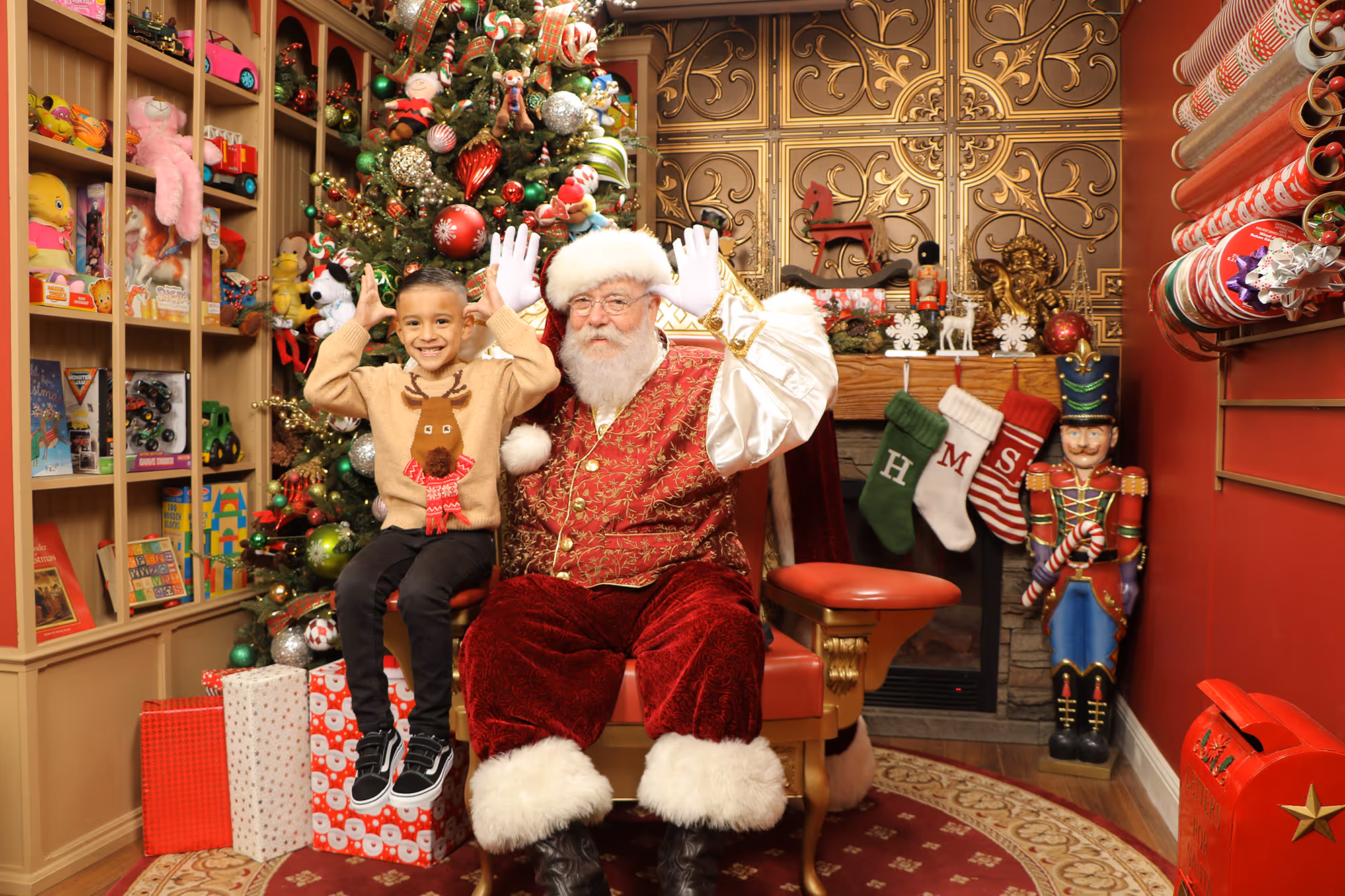 Silly Christmas photo of a boy with Santa and both have their hands on their heads like reindeers