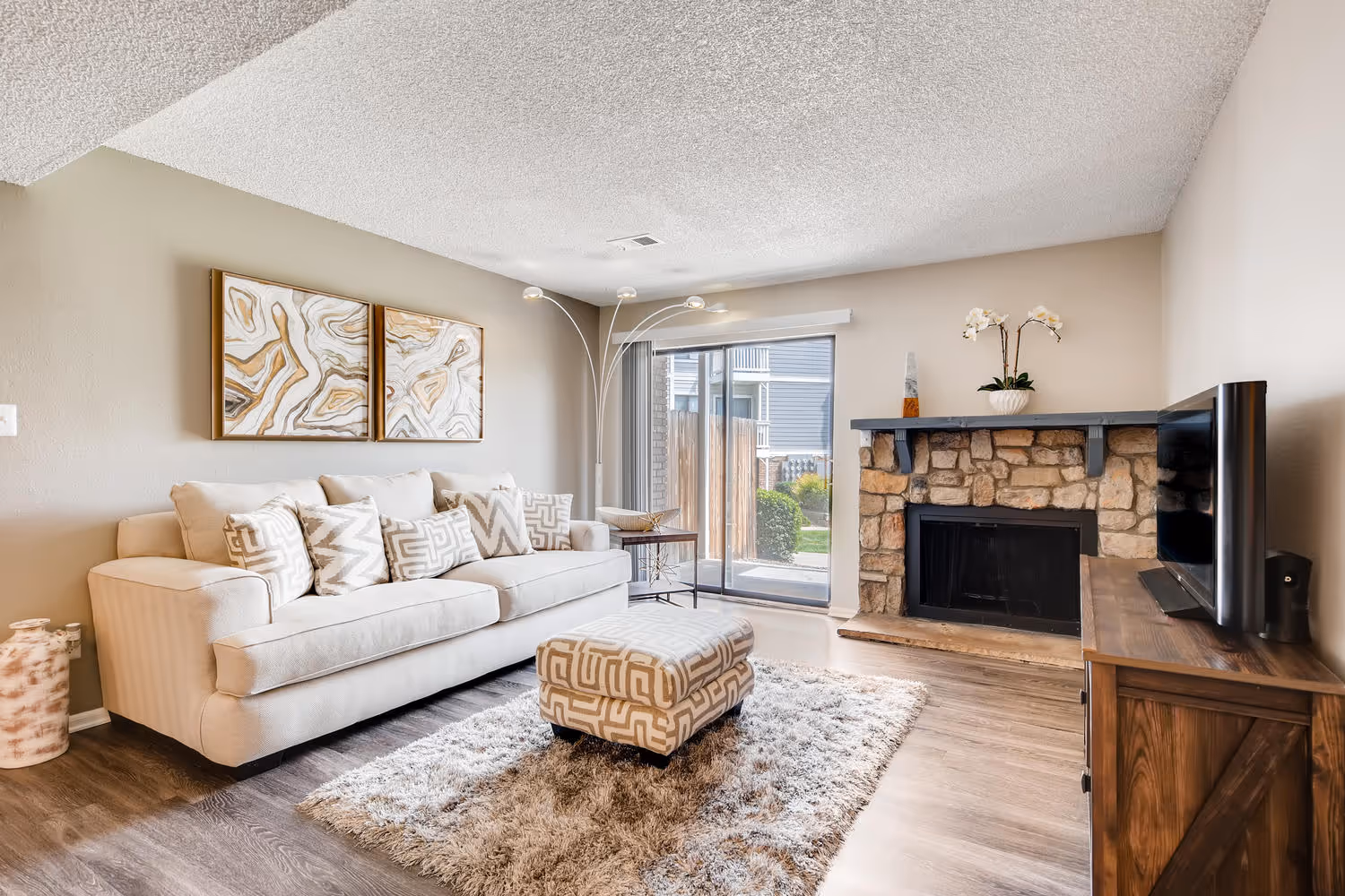 Cozy living room with a stone fireplace, a large sofa, and wood-look flooring, in an apartment at Villas at Holly in Centennial, CO.