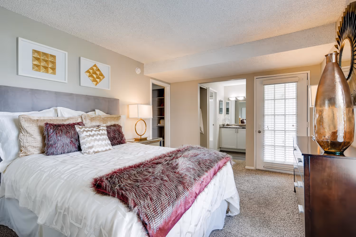 Comfortable bedroom with a bed, plush pillows, and a view into the en-suite bathroom and closet at Villas at Holly in Centennial, CO.