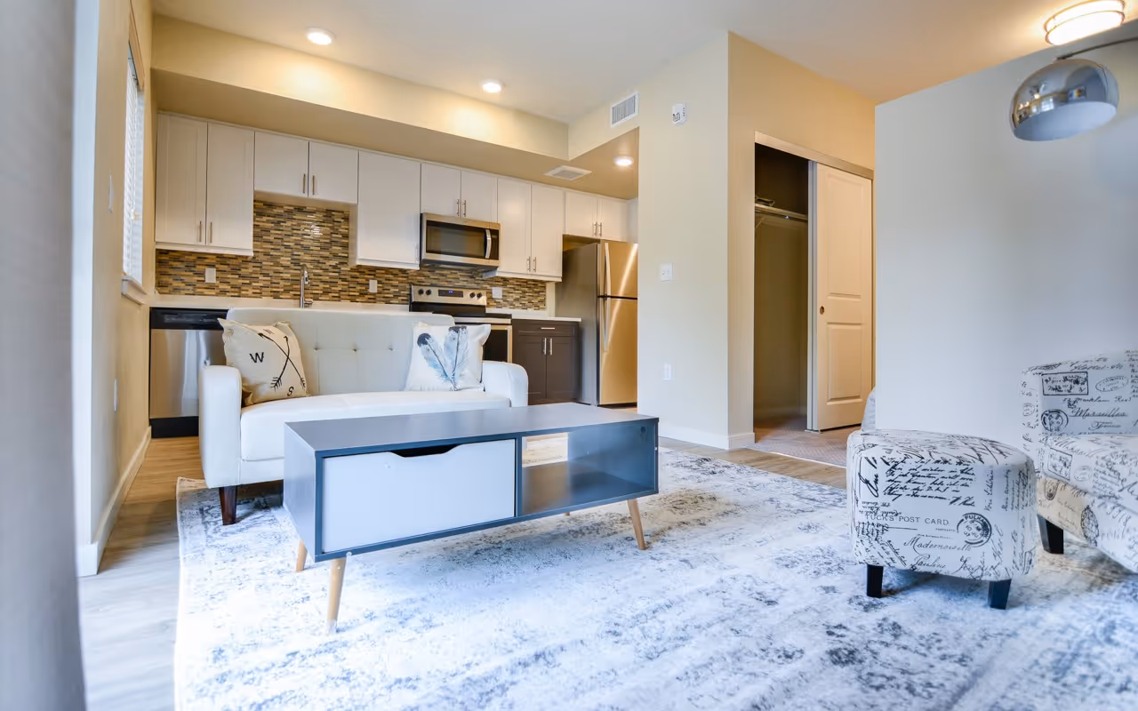 Open-concept living room and kitchen area with a sofa, coffee table, and a view of the two-tone kitchen cabinets, at Villas at Holly in Centennial, CO.