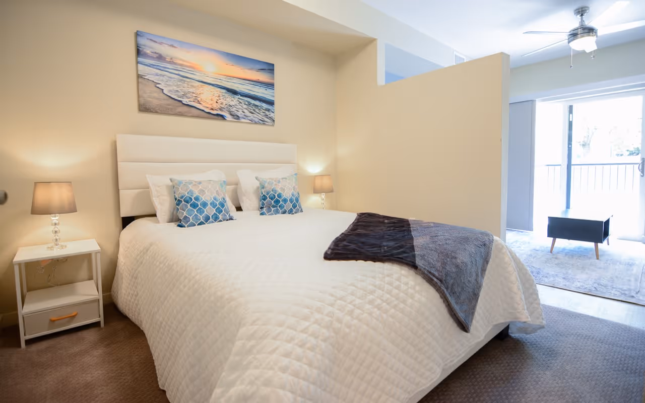 Spacious bedroom with a queen bed, bright art, and a view of the patio, in an apartment at Villas at Holly in Centennial, CO.