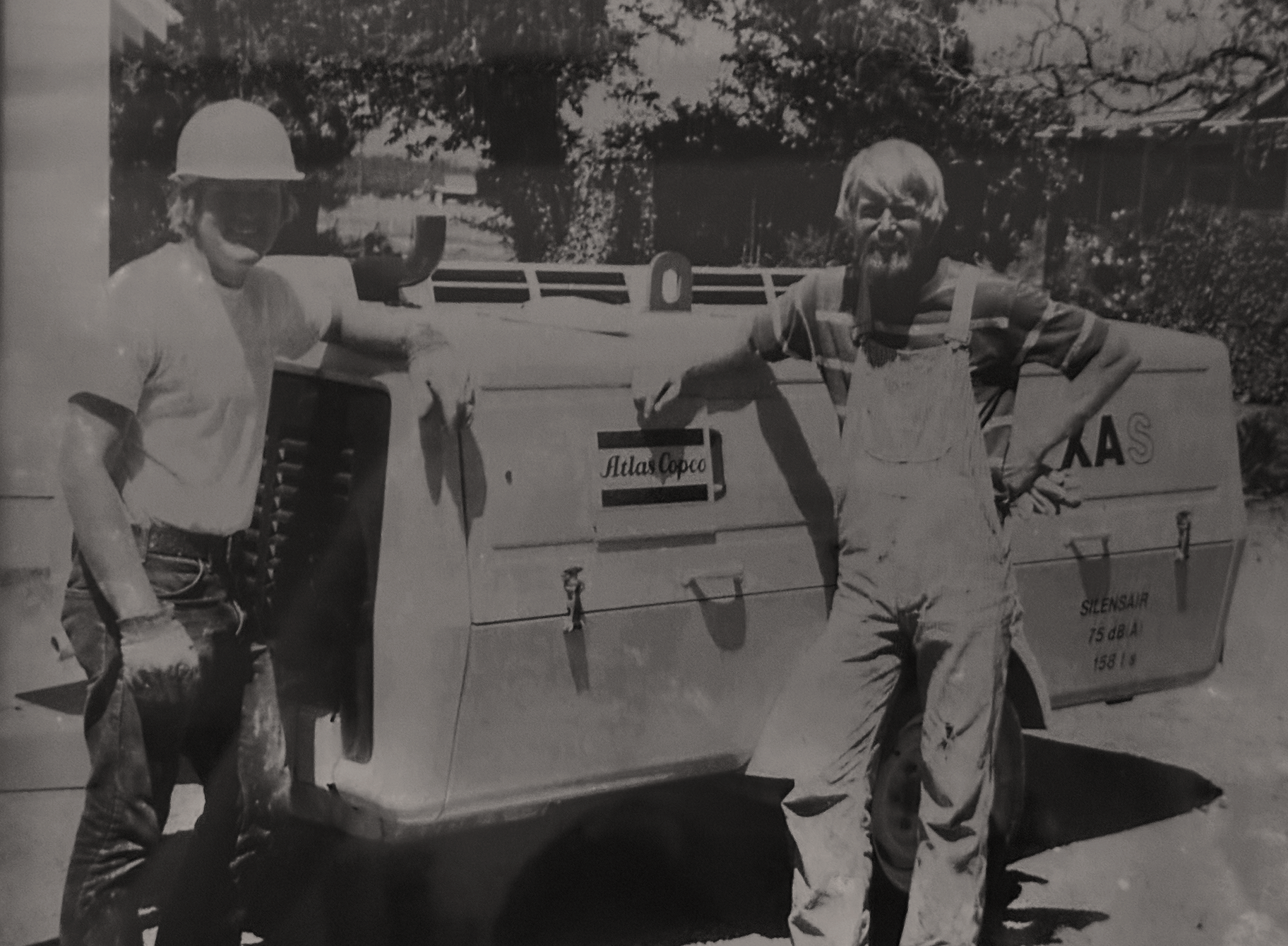 Founders Curtis and Blake Hennings in front of an air compressor.