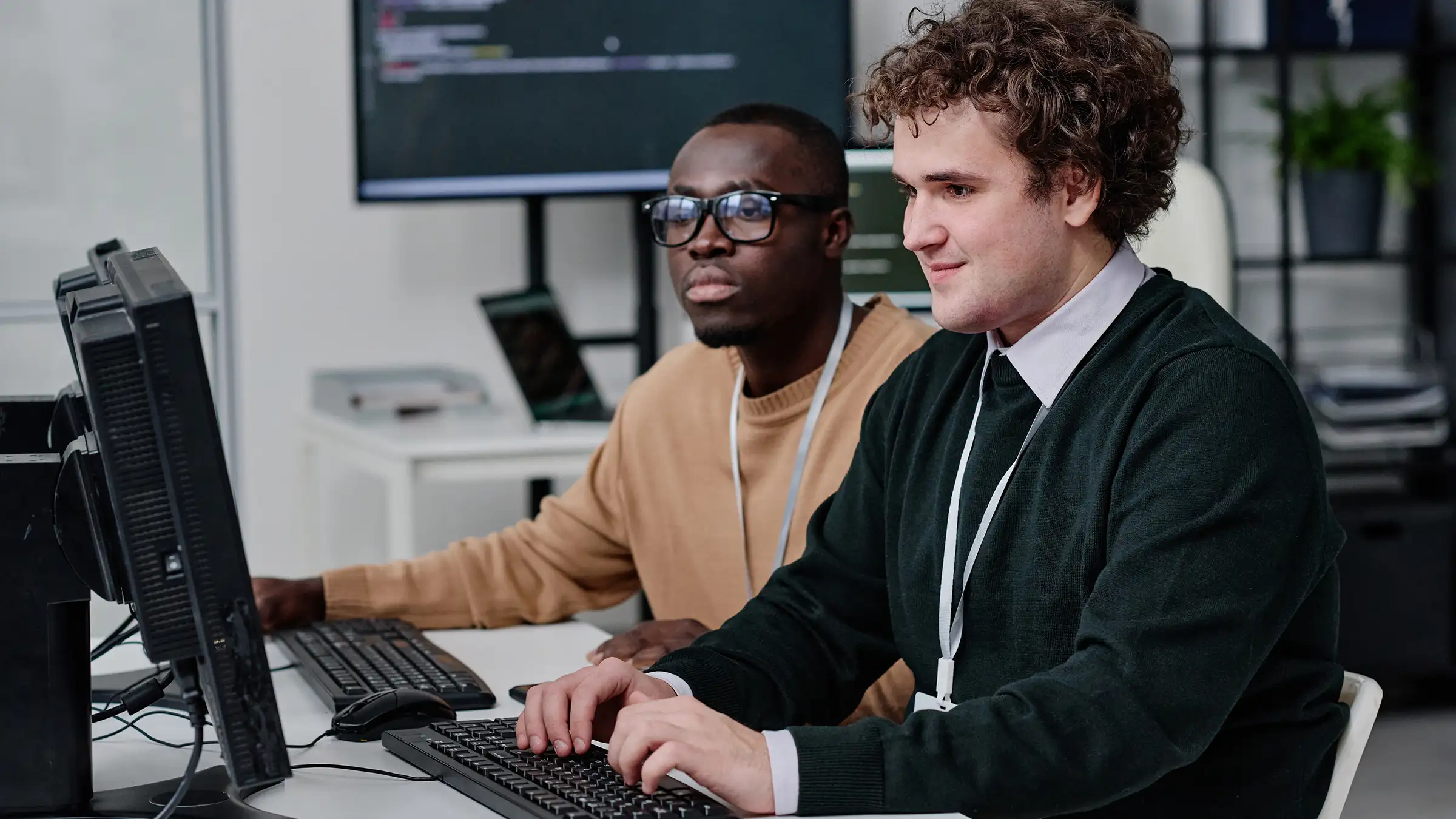Two computer programmers sitting at a computer working on API integration