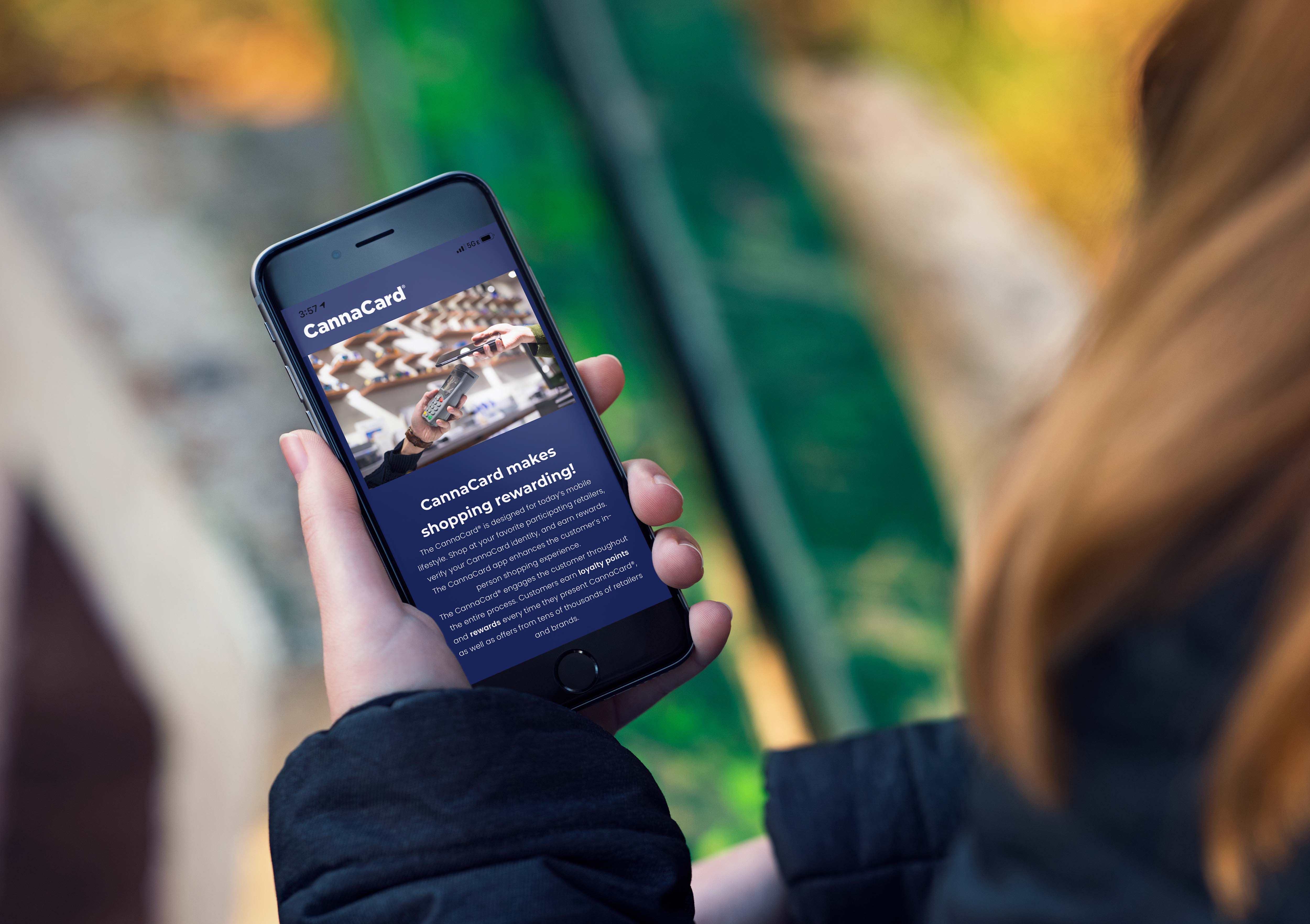 Person holding a smartphone displaying the CannaCard app with information about shopping rewards and loyalty points.