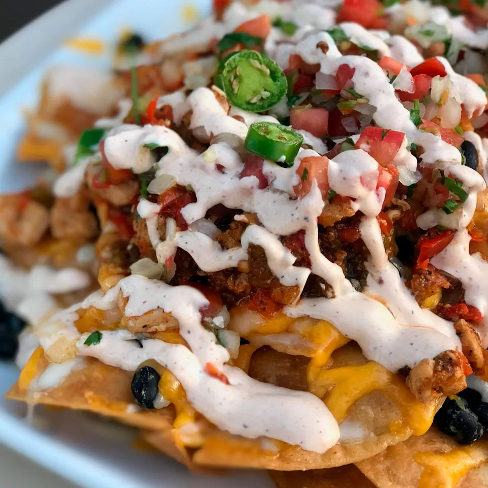 Nachos with cheese, sweet beans, pico de gallo, and green serrano peppers