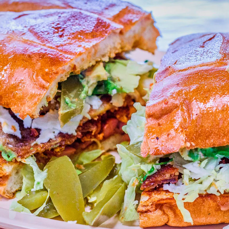 Torta with asada, al pastor and jam. served with lettuce, tomatoes and sour cream.