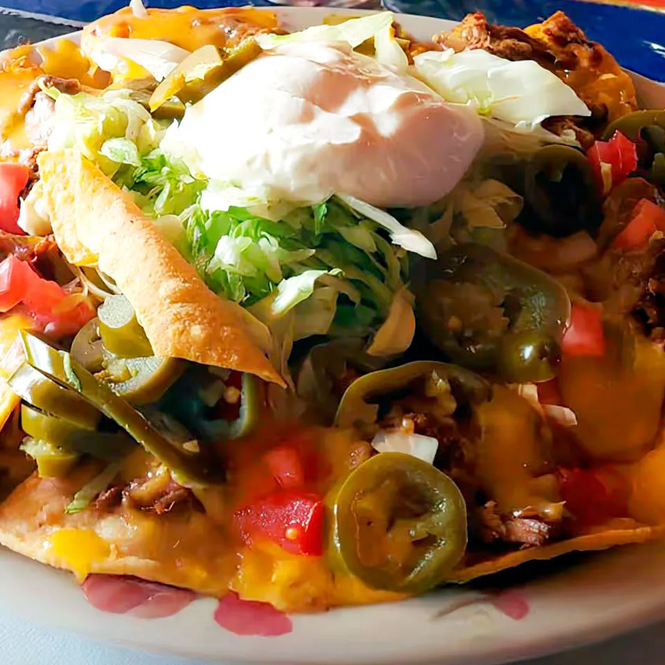 Tostada with steak, beens, onion, tomatoes, cream and slice serrano pepper