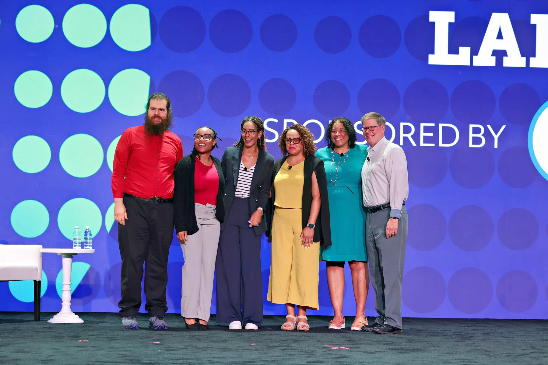 Six individuals from the 2025 Disability:IN Conference smile together on stage at the NextGen iLab session.