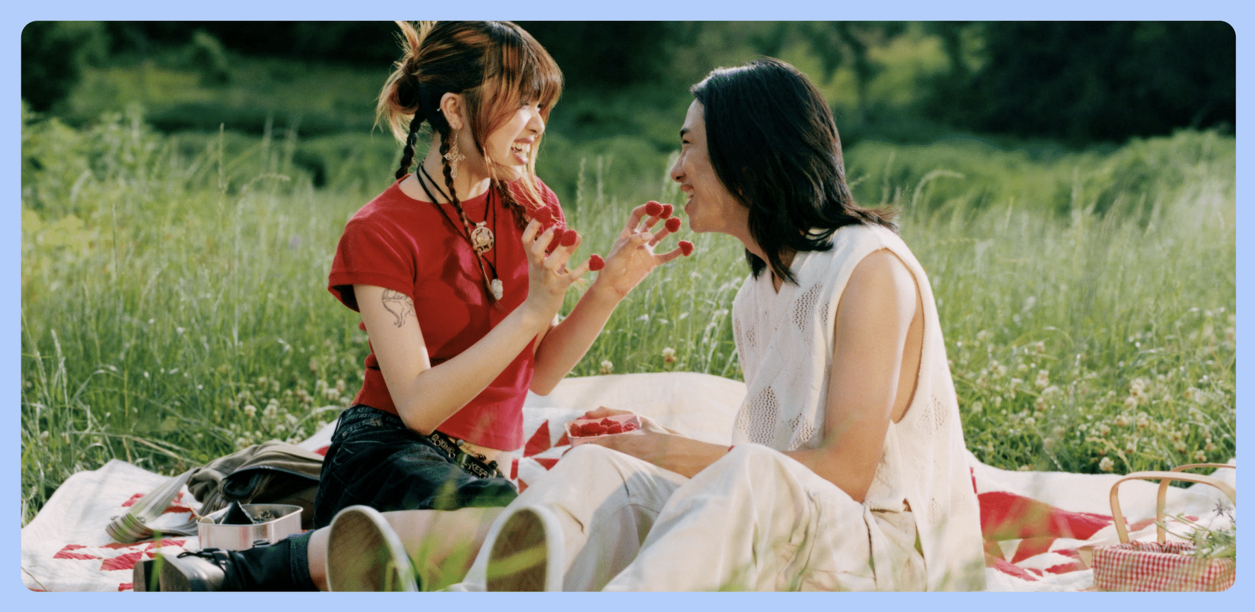 Two individuals smiling and laughing on a picnic in the park.