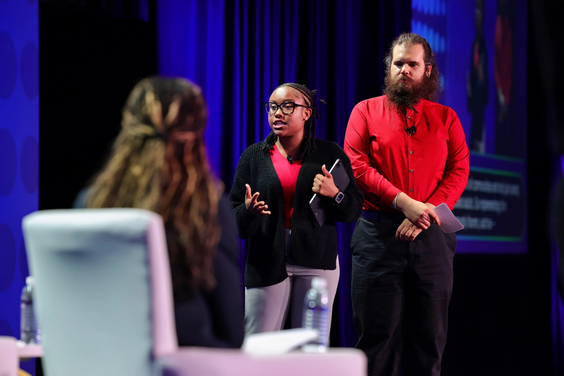 Two young leaders stand and make their pitch to corporate leaders on stage at the disability:IN conference