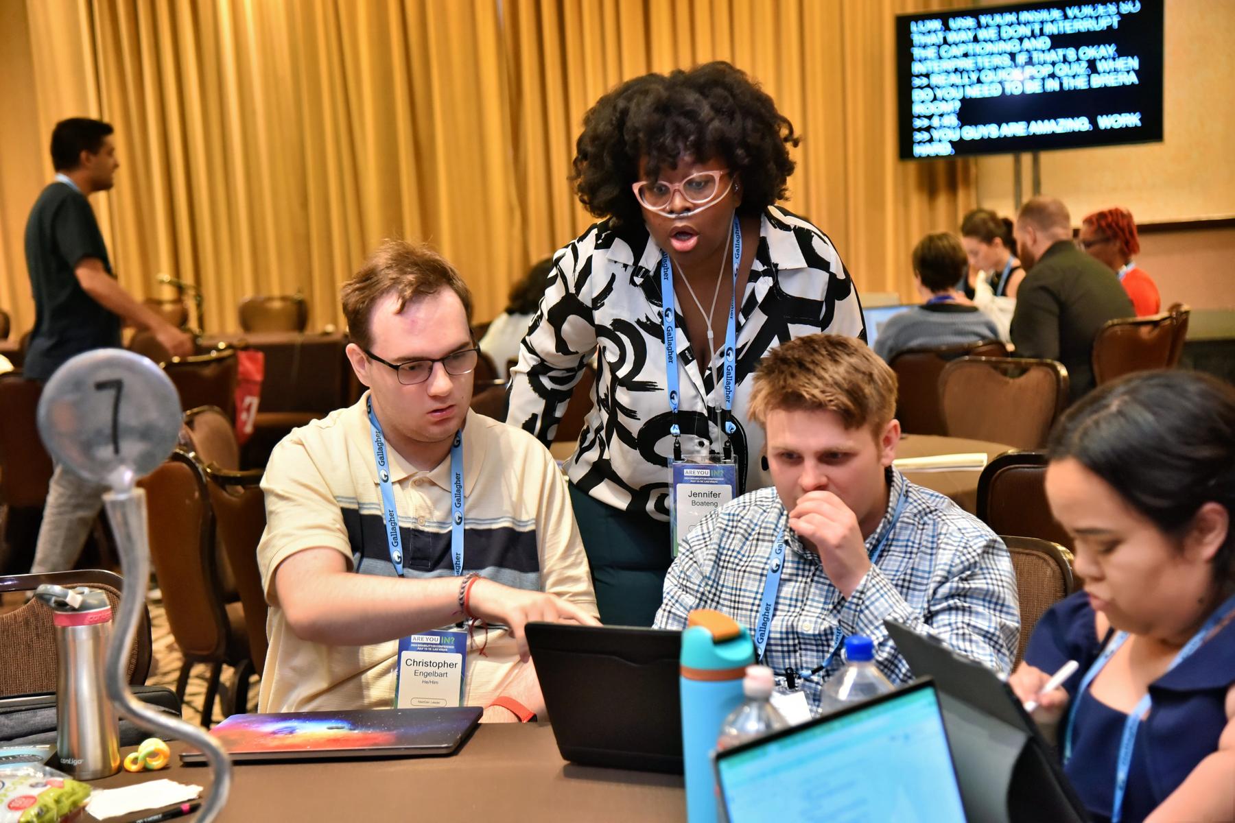 A group of nextgen leaders huddled around laptops as they collaborate on  an innovation project