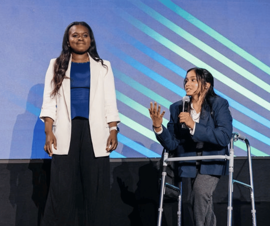 Two NextGen Leaders speak in front of a large audience during the DisabilityIN Conference
