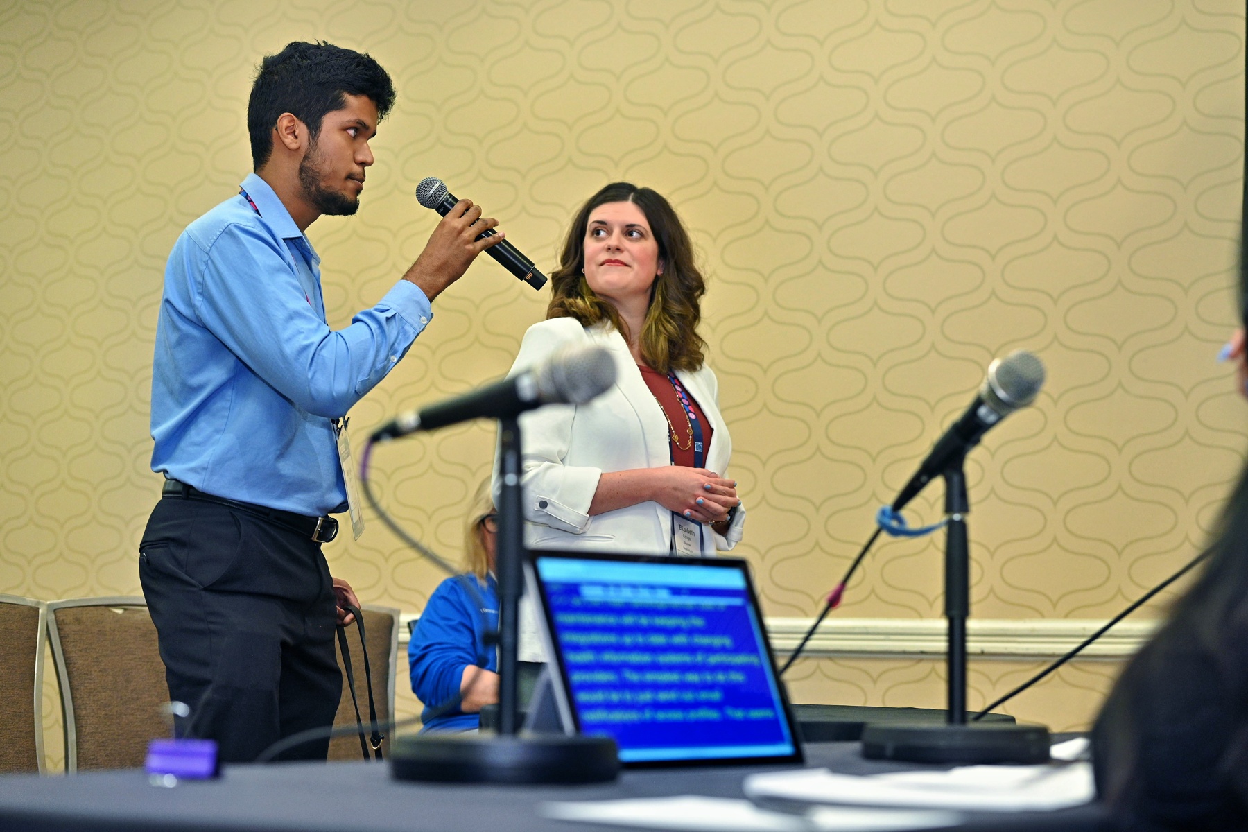 Lizzy and her partner giving a presentation to a group of corporates. Her partner holds a microphone in his hand while Lizzy looks on. 